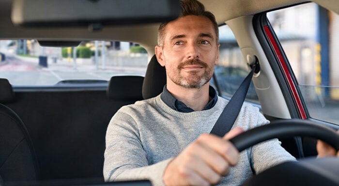 Man driving a car and looking in the rearview mirror