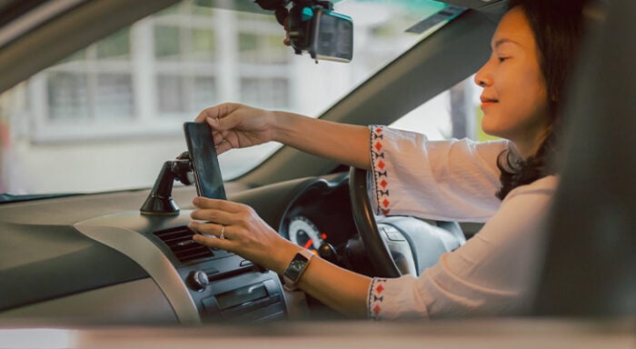 Woman placing her phone on the dashboard