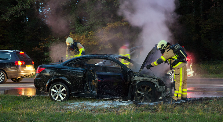 Firefighters watering down fire from car