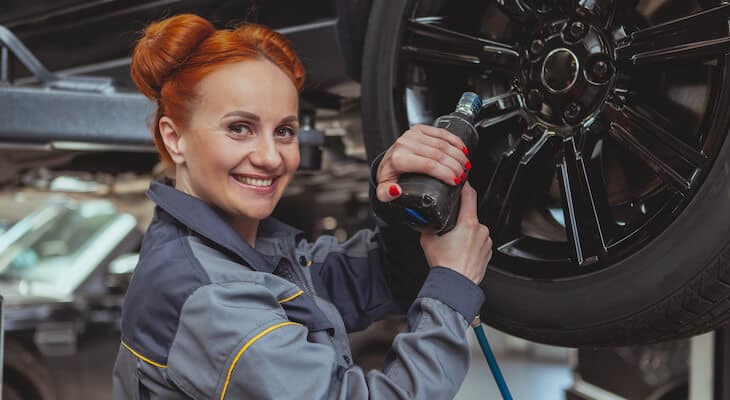 Electric car mechanic smiles at camera