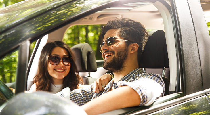 couple with sunglasses smiling in a car 