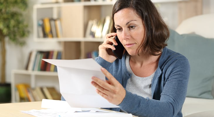 Woman on phone as she reads paperwork