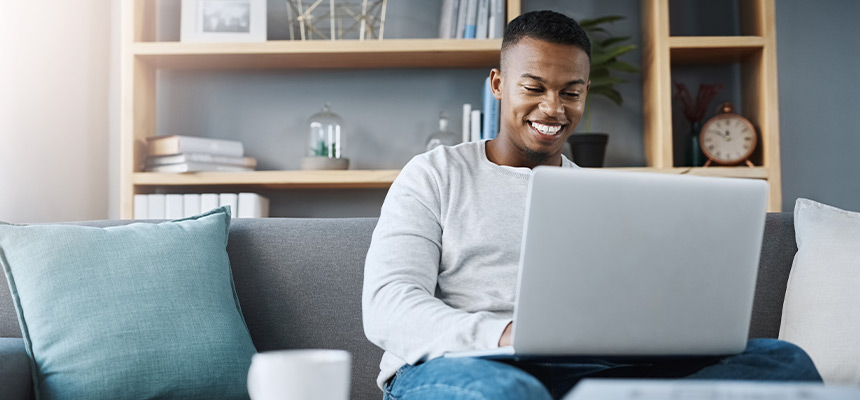 Man smiling and using laptop in living room