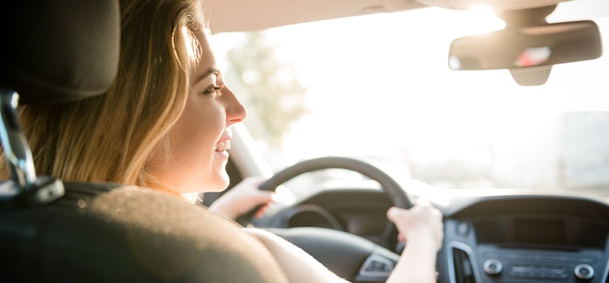 Closeup of a smiling teenager driving a car