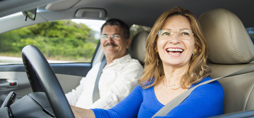 Senior couple driving car and smiling