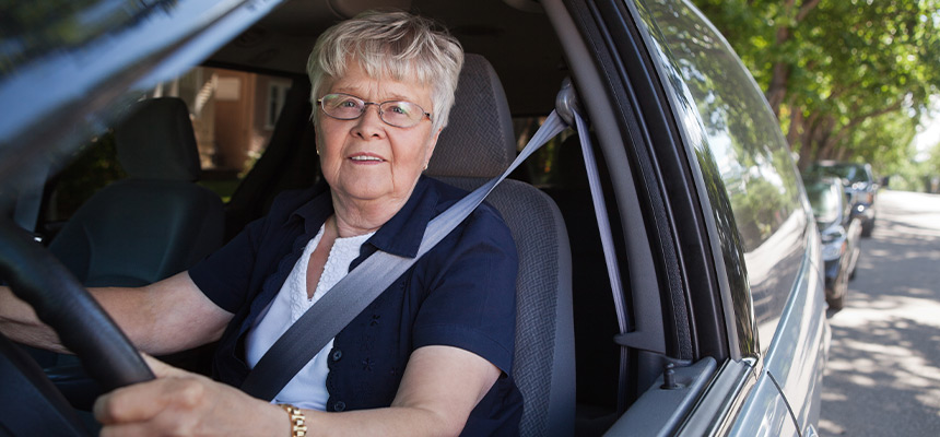 Senior woman smiling and driving car