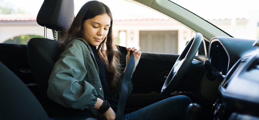 Teenage girl putting seatbelt on