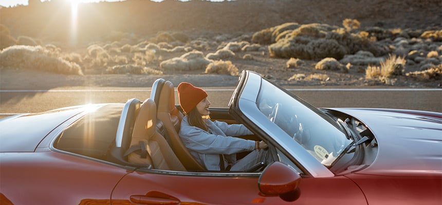 Young woman driving a convertible in a desert backdrop