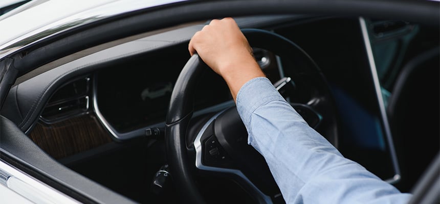 Closeup of hand gripping steering wheel