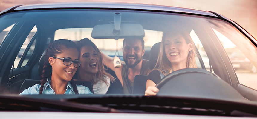 Four friends inside car smiling together