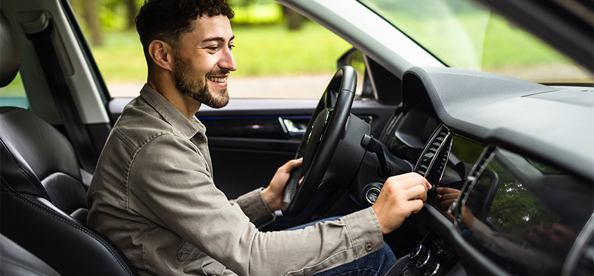 Young man inside car pressing button in car dashboard