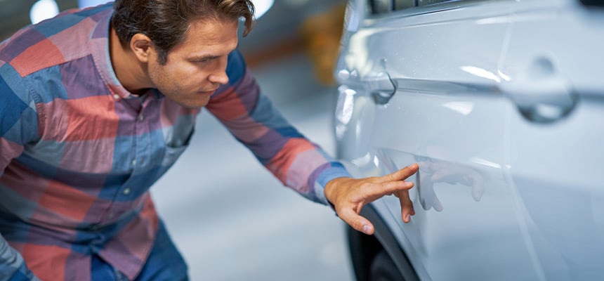 Man inspecting scratch on car door