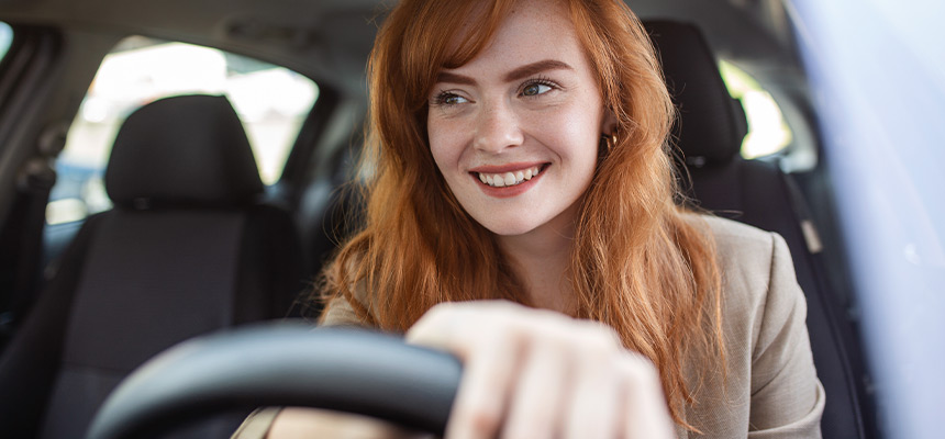 Young woman smiling with hand on wheel