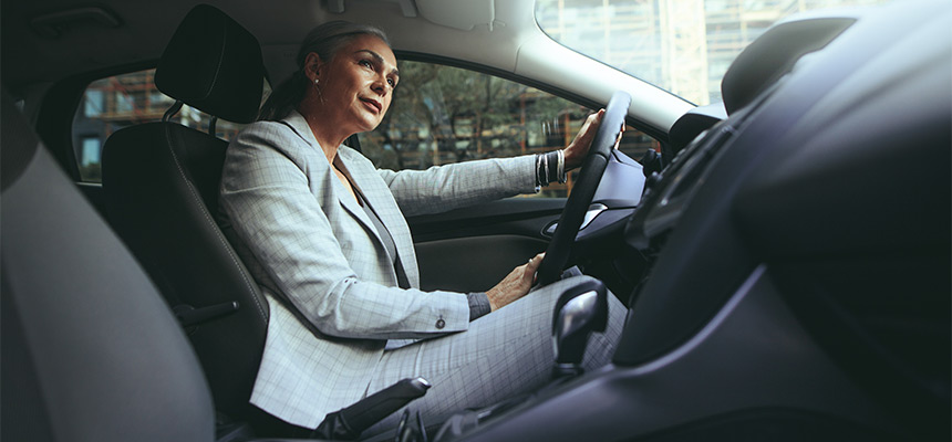 Senior woman wearing grey suit driving