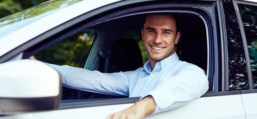 White man smiling at the car whilst inside car