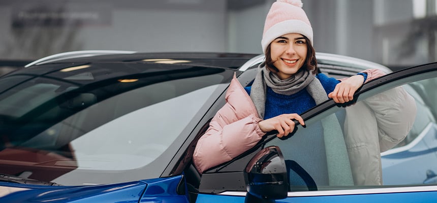 Young woman wearing pink winter gear and beanie while outside car