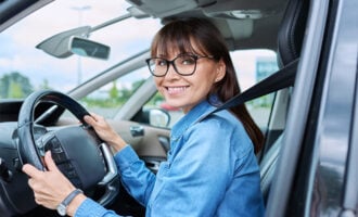 Young woman wearing glasses and denim jacket driving