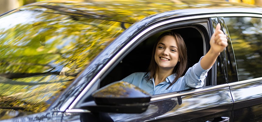 Young woman giving a thumbs up inside car