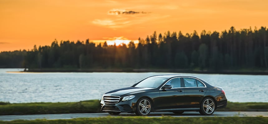 Panoramic view of black luxury car with sunset backdrop