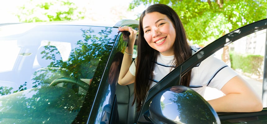 Smiling rideshare driver posing by their car