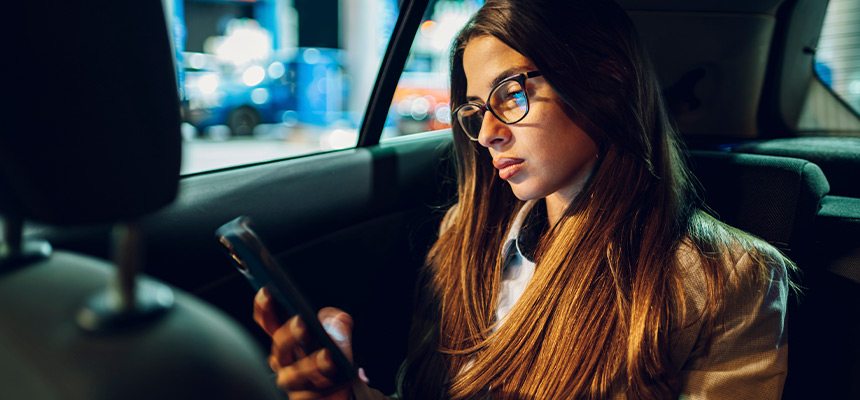 Female passenger using their phone during the night inside car