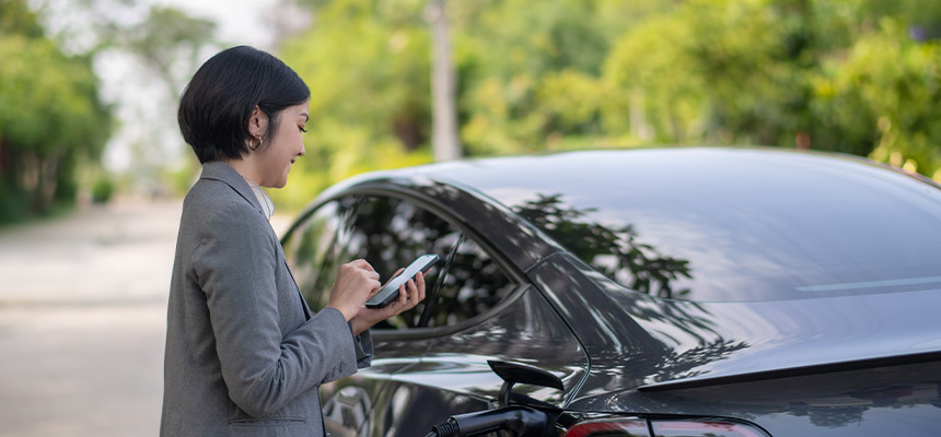 Young woman using her phone outside of car